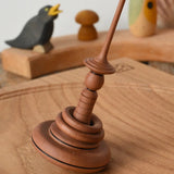 Mader Helene's Captive Rings Apple Spinning Top paced on an oak spinning board.