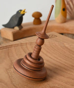Mader Helene's Captive Rings Apple Spinning Top paced on an oak spinning board.
