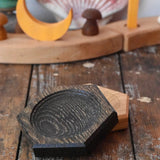 Mader hexagon 8cm spinning top plates in black oak and oak placed on a wooden surface in the Babipur playroom.