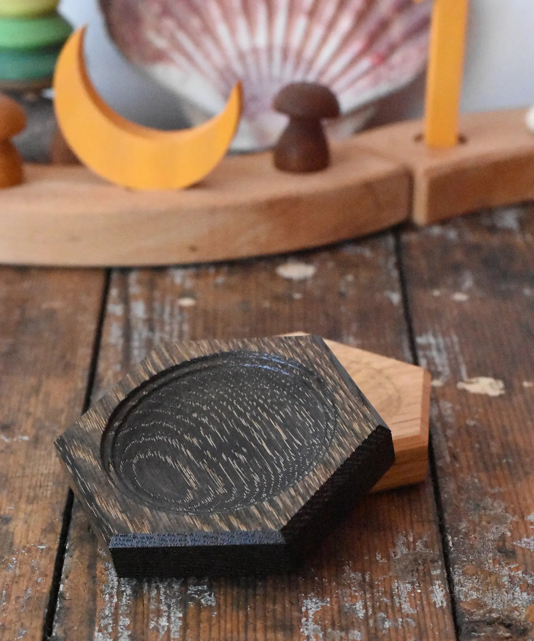 Mader hexagon 8cm spinning top plates in black oak and oak placed on a wooden surface in the Babipur playroom.