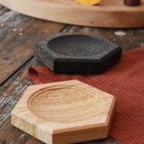 Mader hexagon 8cm spinning top plates in oak and black oak placed on a wooden surface in the Babipur playroom. 