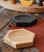 Mader hexagon 8cm spinning top plates in oak and black oak placed on a wooden surface in the Babipur playroom. 