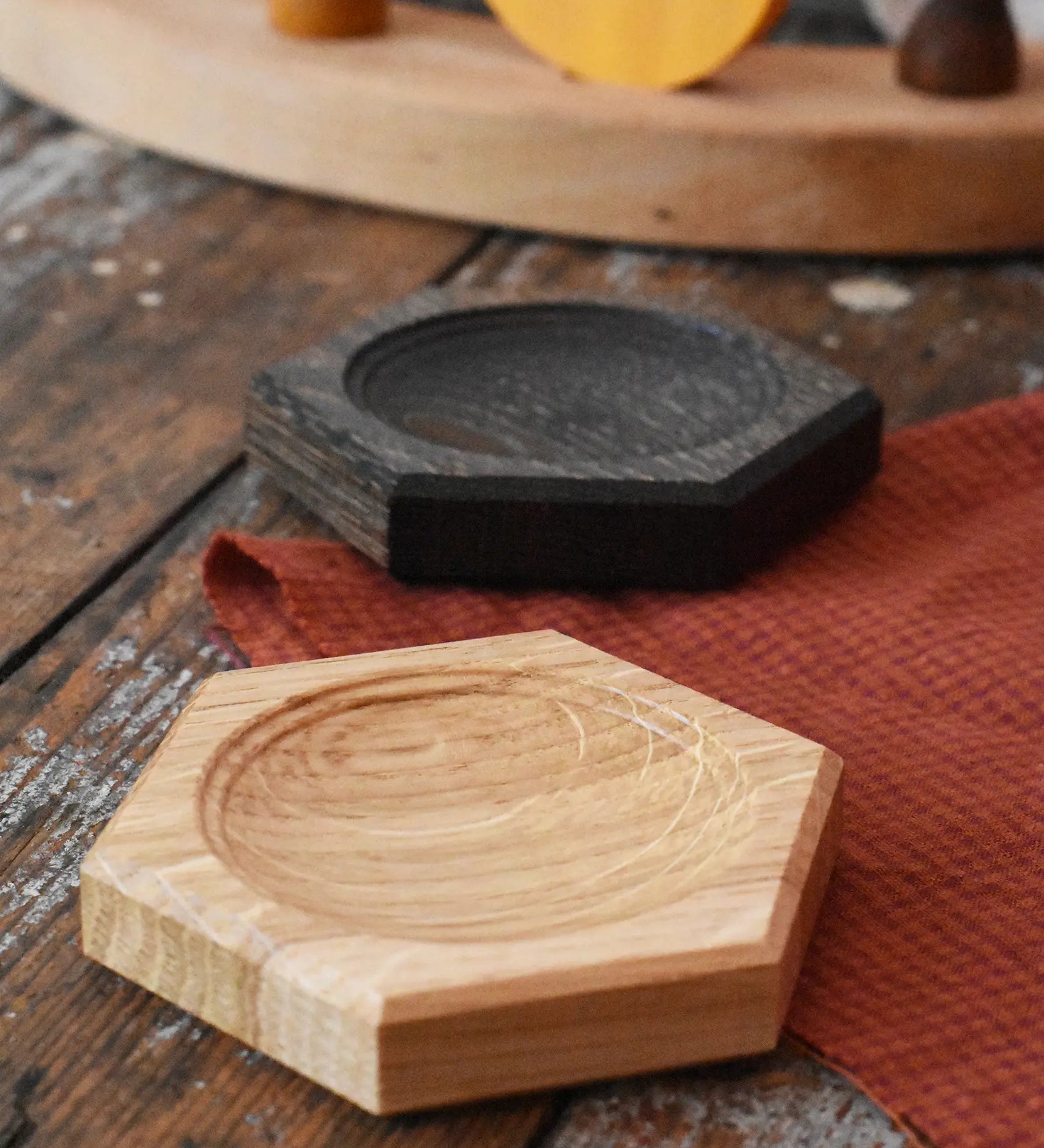 Mader hexagon 8cm spinning top plates in oak and black oak placed on a wooden surface in the Babipur playroom. 