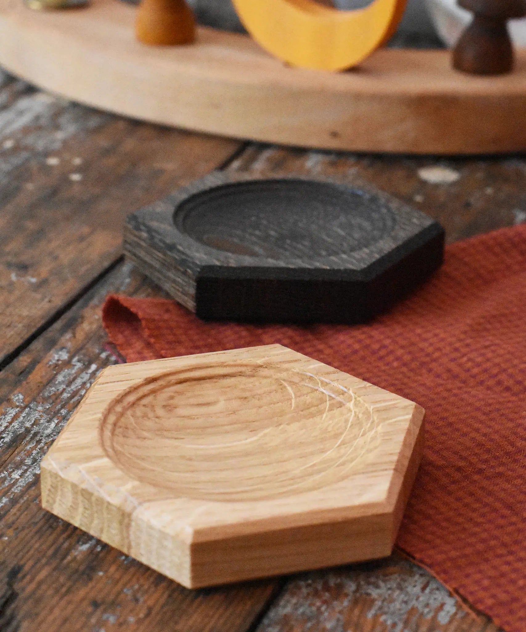 Mader hexagon 8cm spinning top plates in oak and black oak placed on a wooden surface in the Babipur playroom. 