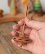 Mader ibis spinning top in an adult's hand.