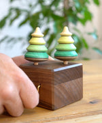 Close up of a hand turning the Mader wooden music box on a wooden table