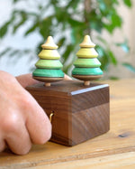 Close up of a hand turning the Mader wooden music box on a wooden table