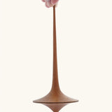 Mader handmade wooden 75mm Trumpo spinning top, an adult hand can be seen holding it upright.