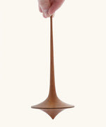 Mader handmade wooden 75mm Trumpo spinning top, an adult hand can be seen holding it upright.