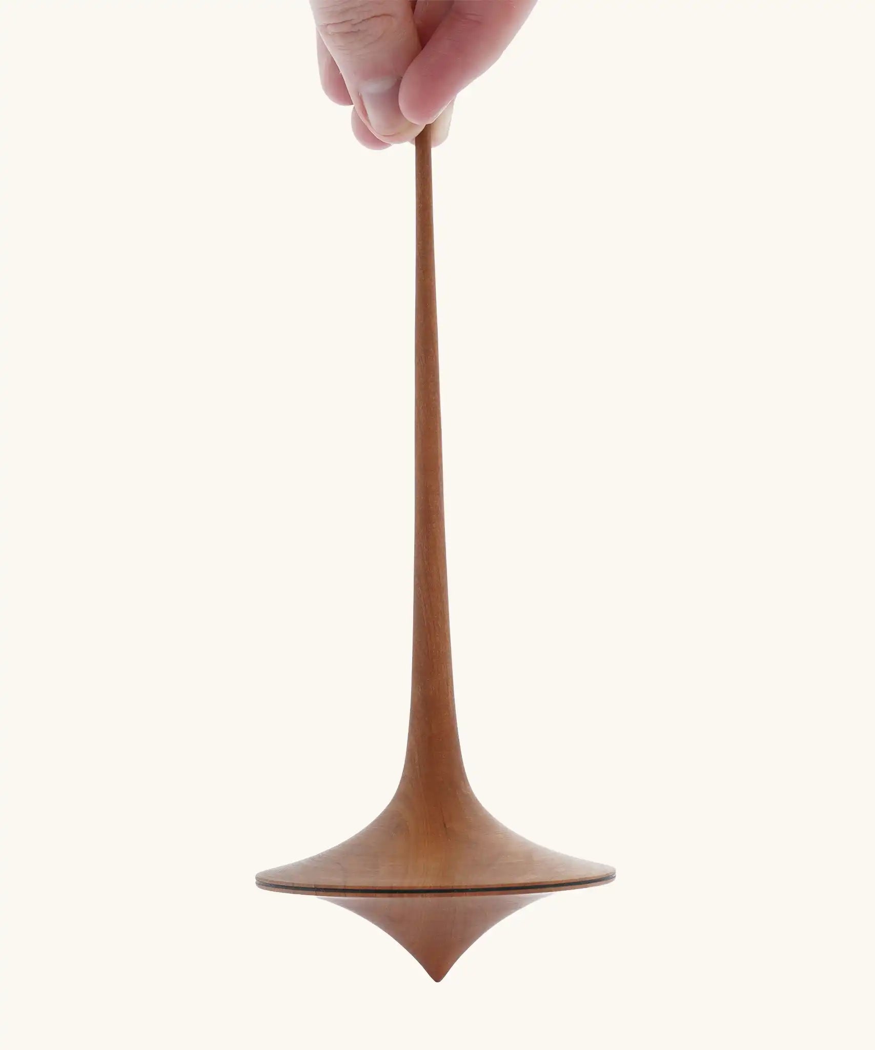 Mader handmade wooden 75mm Trumpo spinning top, an adult hand can be seen holding it upright.
