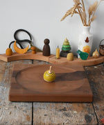 Mader yellow bee spinning top spinning on a Mader Kreiselmanufaktur Large 25cm Walnut Spinning Plate placed on a wooden surface in the Babipur playroom.