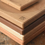 A stack of handmade Mader spinning plates in different woods, cherry, ash, walnut and oak placed on a wooden surface in the Babipur playroom. 