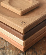 A stack of handmade Mader spinning plates in different woods, cherry, ash, walnut and oak placed on a wooden surface in the Babipur playroom. 