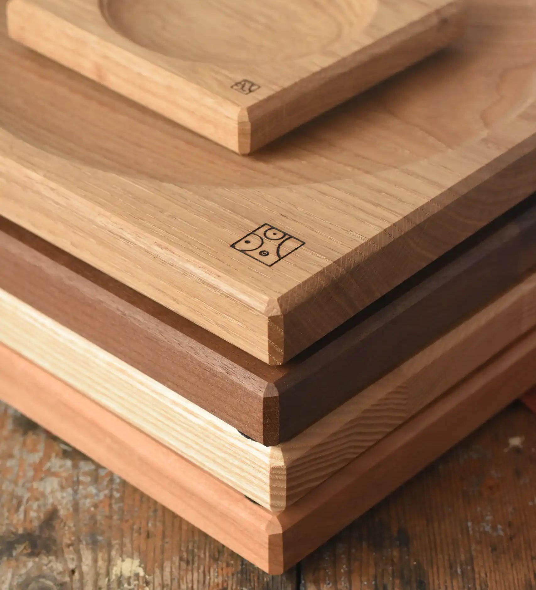 A stack of handmade Mader spinning plates in different woods, cherry, ash, walnut and oak placed on a wooden surface in the Babipur playroom. 