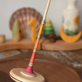 Mader Kreiselmanufaktur Large red Arabella Spinning Top  placed on a walnut wood spinning plate. 