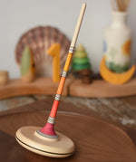 Mader Kreiselmanufaktur Large red Arabella Spinning Top  placed on a walnut wood spinning plate. 