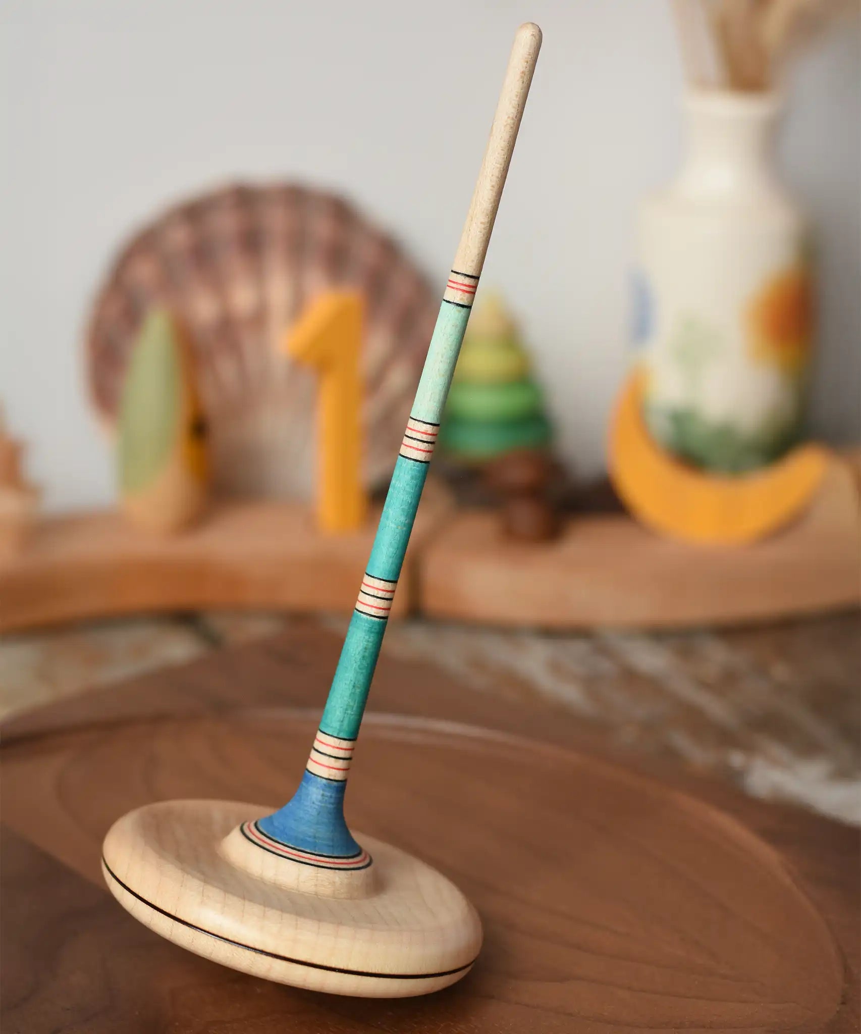 Mader Kreiselmanufaktur Large Arabella Spinning Top placed on a walnut wood spinning plate. 