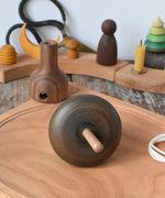 Mader pull-string tree spinning top placed on a cherry wood spinning plate in the Babipur playroom. The bottom of the spinner is shown