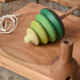 Mader pull-string tree spinning top placed on a cherry wood spinning plate in the Babipur playroom.