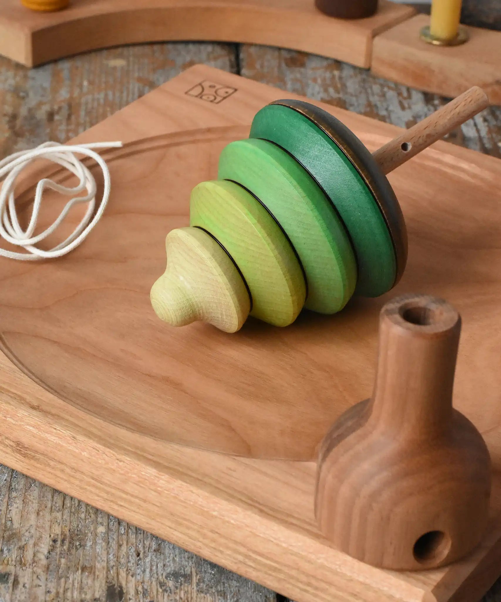 Mader pull-string tree spinning top placed on a cherry wood spinning plate in the Babipur playroom.