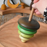 Mader pull-string tree spinning top placed on a cherry wood spinning plate in the Babipur playroom.