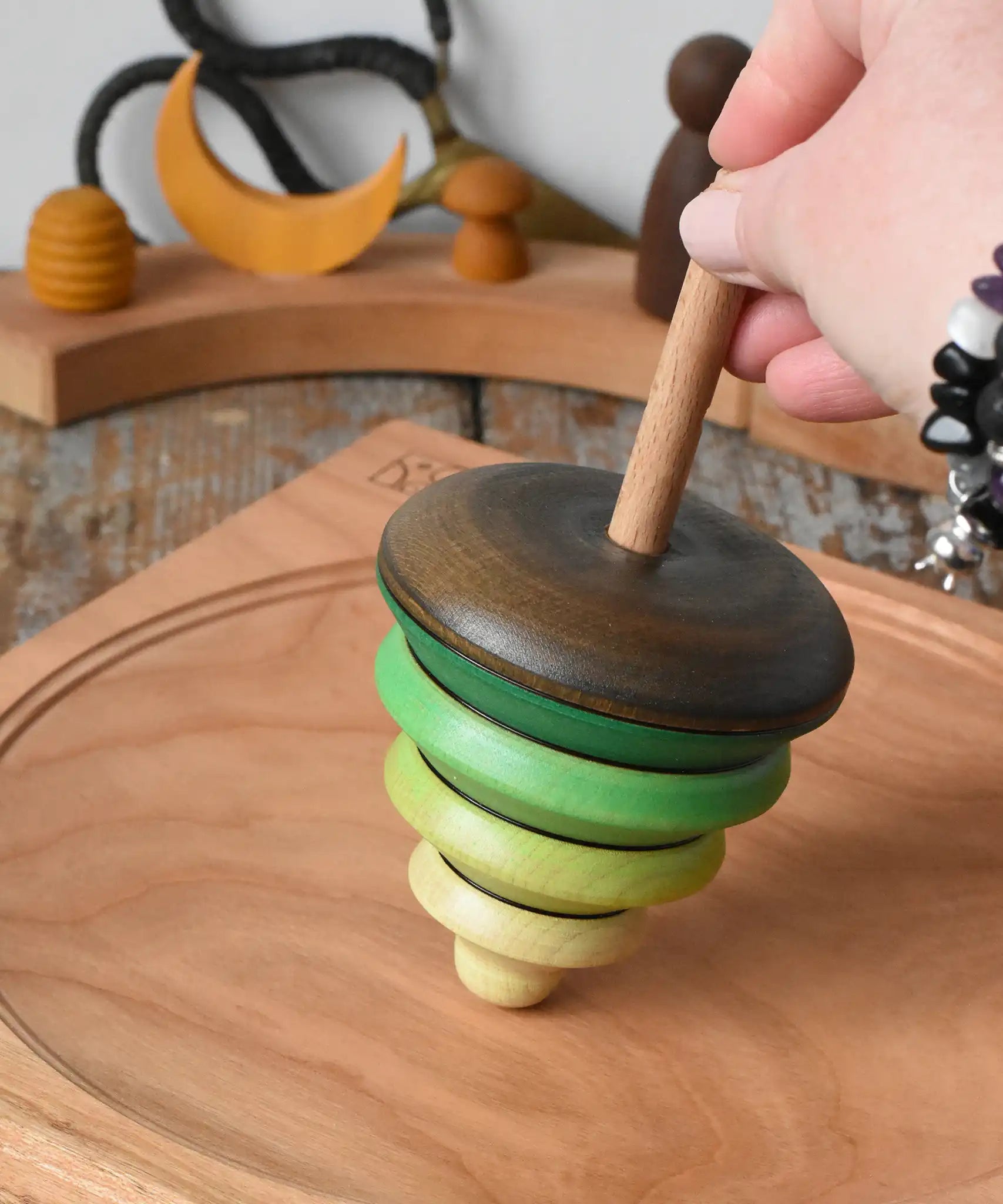Mader pull-string tree spinning top placed on a cherry wood spinning plate in the Babipur playroom.