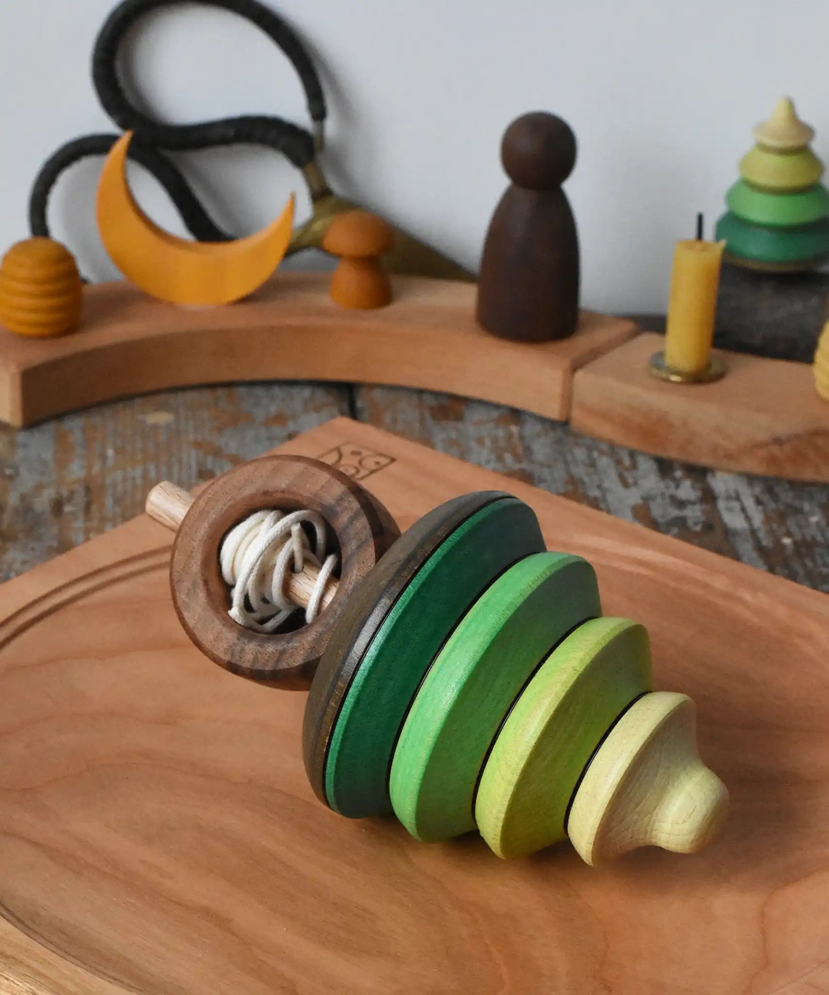 Mader pull-string tree spinning top placed on a cherry wood spinning plate in the Babipur playroom.