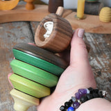 Mader pull-string tree spinning top in an adult's hand in the Babipur playroom.