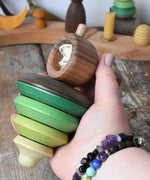 Mader pull-string tree spinning top in an adult's hand in the Babipur playroom.