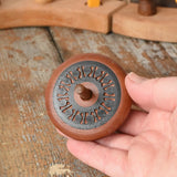 Mader Kreiselmanufaktur leporello wooden spinning top in an adult's hand in the Babipur playroom.