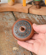Mader Kreiselmanufaktur leporello wooden spinning top in an adult's hand in the Babipur playroom.