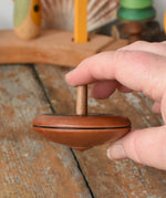 Mader Kreiselmanufaktur leporello wooden spinning top in an adult's hand. 