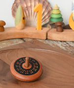 Mader Kreiselmanufaktur leporello wooden spinning top placed on a walnut spinning plate in the Babipur playroom.