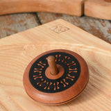Mader Kreiselmanufaktur leporello wooden spinning top placed on an ash wood spinning plate in the Babipur playroom.