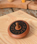 Mader Kreiselmanufaktur leporello wooden spinning top placed on an ash wood spinning plate in the Babipur playroom.
