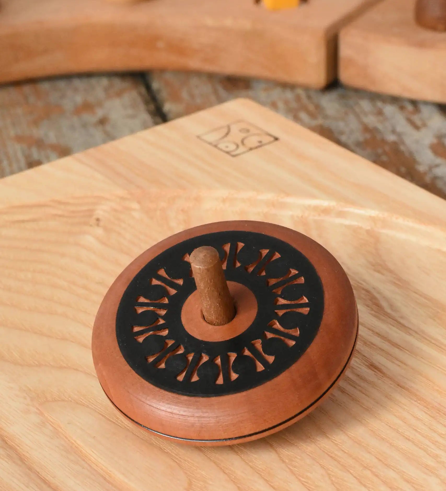 Mader Kreiselmanufaktur leporello wooden spinning top placed on an ash wood spinning plate in the Babipur playroom.