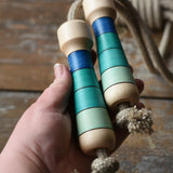 Mader Kreiselmanufaktur Skipping Rope with blue striped wooden handles in an adult's hand. 