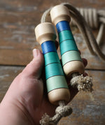 Mader Kreiselmanufaktur Skipping Rope with blue striped wooden handles in an adult's hand. 