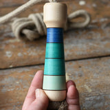 Mader Kreiselmanufaktur Skipping Rope with blue striped wooden handles placed on a wooden surface in the Babipur playroom. 