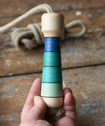 Mader Kreiselmanufaktur Skipping Rope with blue striped wooden handles placed on a wooden surface in the Babipur playroom. 