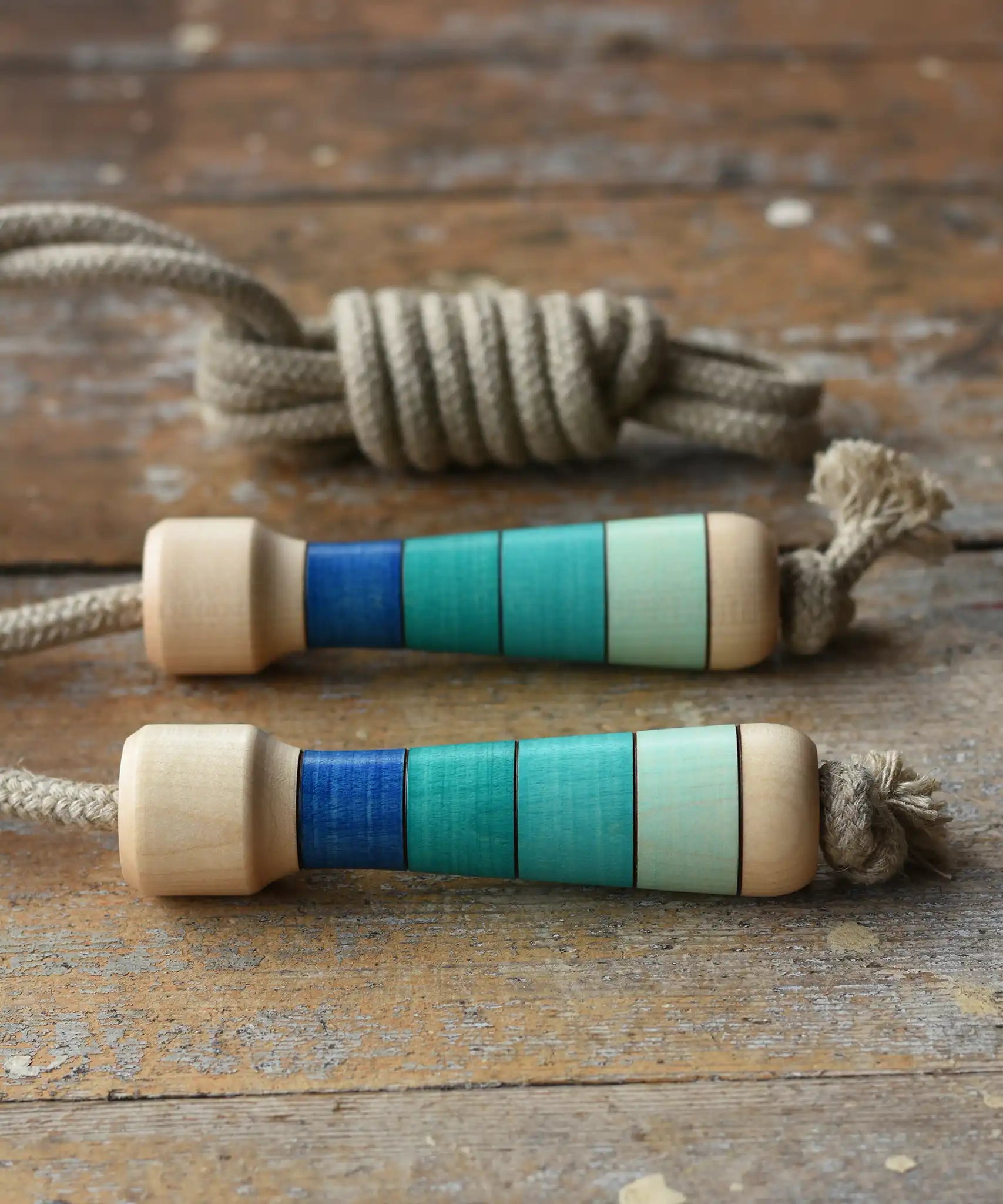 Mader Kreiselmanufaktur Skipping Rope with blue striped wooden handles placed on a wooden surface in the Babipur playroom. 