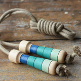 Mader Kreiselmanufaktur Skipping Rope with blue striped wooden handles placed on a wooden surface in the Babipur playroom. 