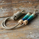 Mader Kreiselmanufaktur Skipping Rope with blue striped wooden handles placed on a wooden surface in the Babipur playroom. 