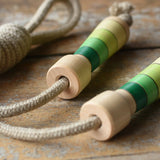 Mader Kreiselmanufaktur Skipping Rope with green striped wooden handles placed on a wooden board in the Bbaipur playroom.