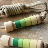 Mader Kreiselmanufaktur Skipping Rope with green striped wooden handles placed on a wooden board in the Bbaipur playroom.