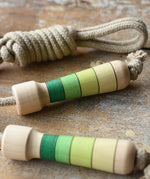 Mader Kreiselmanufaktur Skipping Rope with green striped wooden handles placed on a wooden board in the Bbaipur playroom.