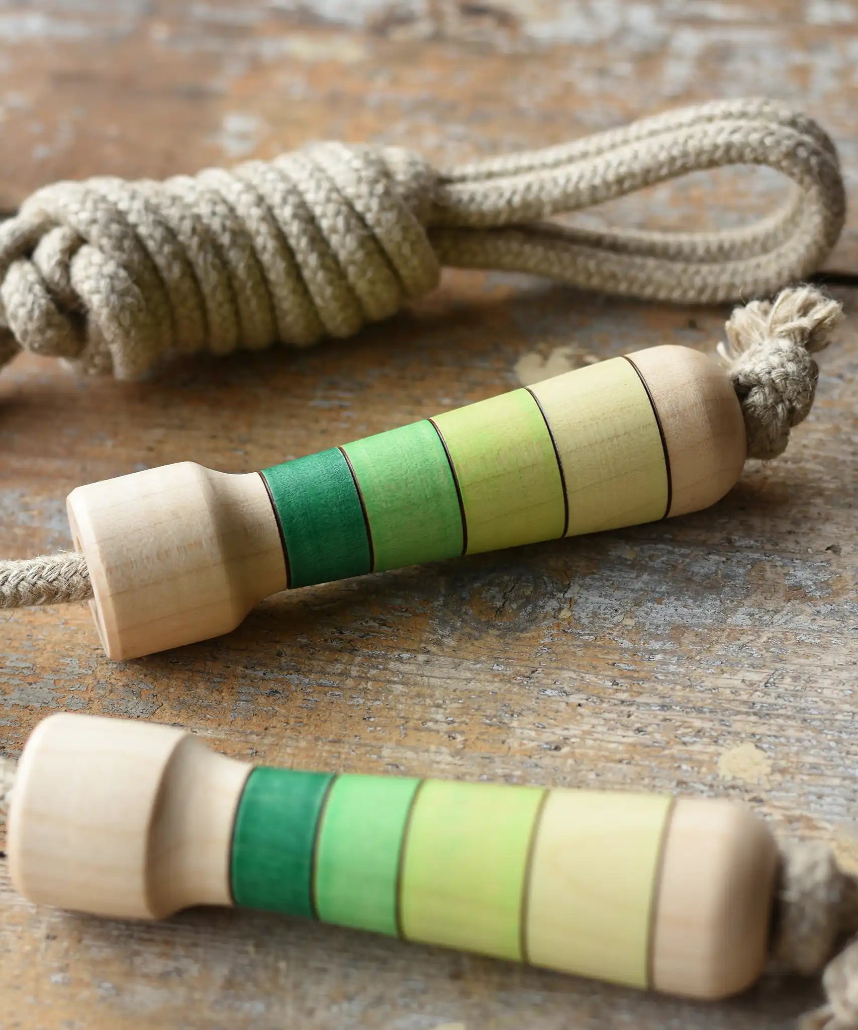 Mader Kreiselmanufaktur Skipping Rope with green striped wooden handles placed on a wooden board in the Bbaipur playroom.