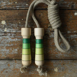 Mader Kreiselmanufaktur Skipping Rope with green striped wooden handles placed on a wooden board in the Bbaipur playroom.