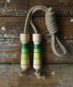 Mader Kreiselmanufaktur Skipping Rope with green striped wooden handles placed on a wooden board in the Bbaipur playroom.