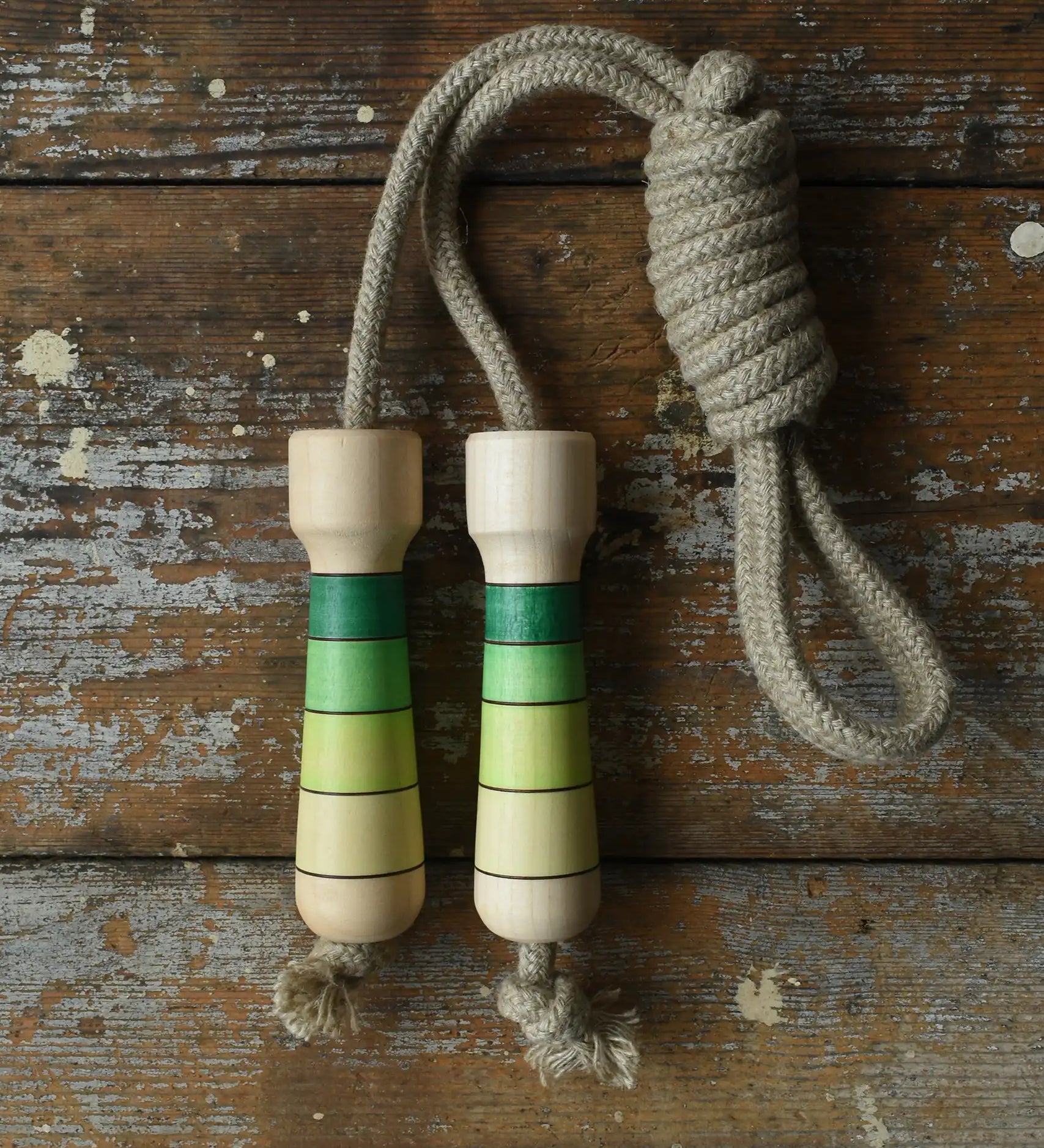 Mader Kreiselmanufaktur Skipping Rope with green striped wooden handles placed on a wooden board in the Bbaipur playroom.